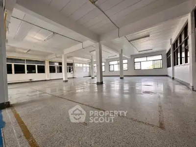 Spacious industrial-style open space with large windows and polished concrete floors.