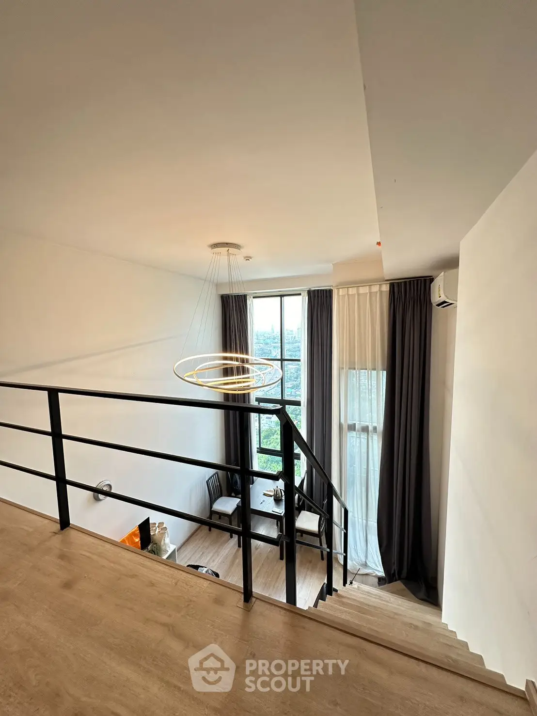 Modern loft apartment with stylish lighting and large window offering a stunning city view.