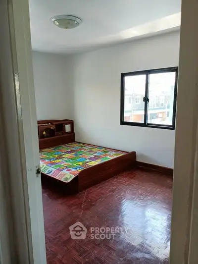 Cozy bedroom with wooden flooring and natural light from window