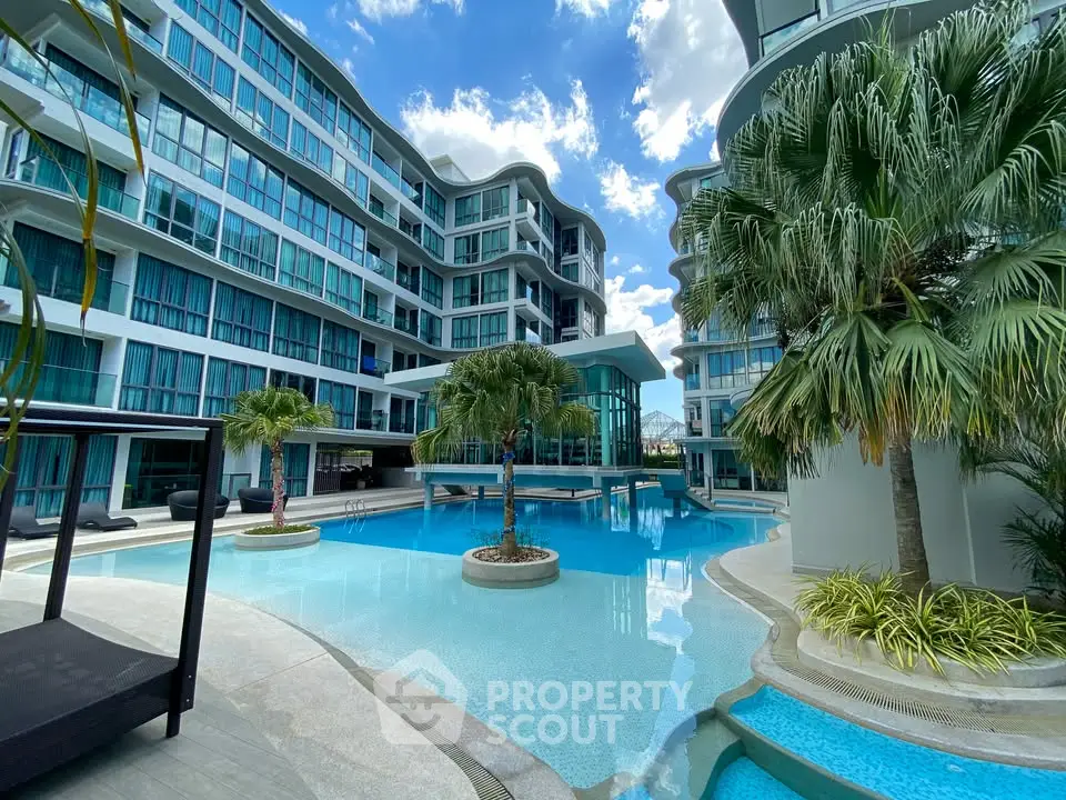 Luxurious modern apartment complex with stunning pool and palm trees under a bright blue sky.