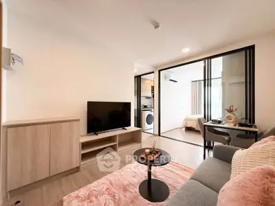 Modern living room with cozy decor and open view into bedroom, featuring stylish furniture and natural light.
