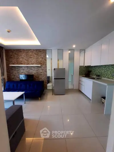 Modern open-layout living room with sleek kitchen and stylish stone accent wall.