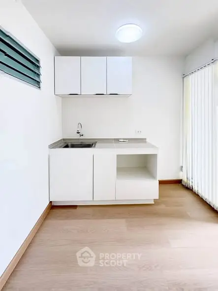 Modern minimalist kitchen with sleek white cabinetry and wooden flooring