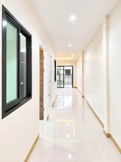 Bright and spacious corridor with modern design and glossy tiled flooring.