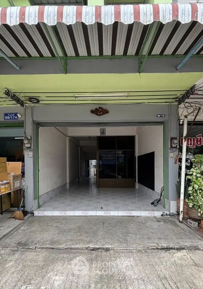 Spacious garage with tiled flooring and retractable awning, ideal for storage or parking.