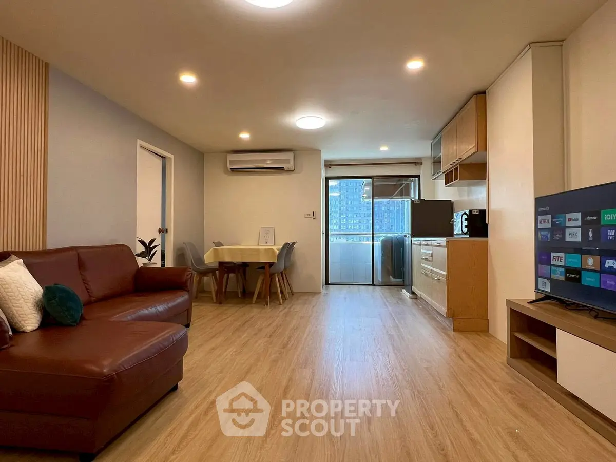 Spacious living room with modern kitchen and balcony view, perfect for urban living.