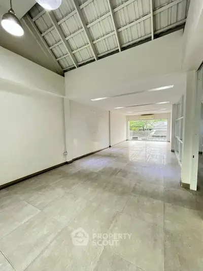 Spacious open-plan interior with high ceilings and large windows offering natural light.