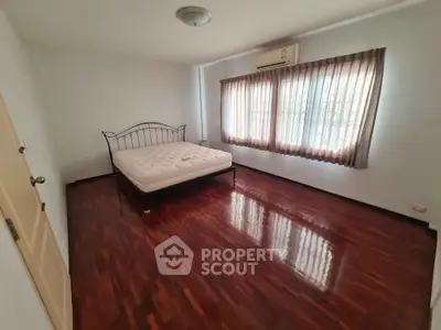 Spacious bedroom with polished wooden floors and natural light