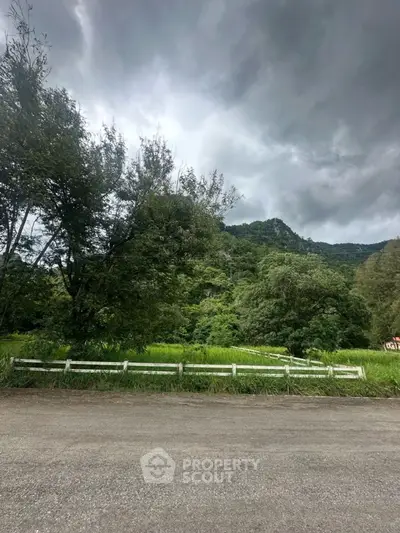Scenic view of lush greenery and mountains under a cloudy sky, perfect for nature lovers.