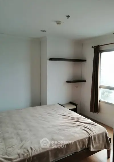 Spacious bedroom with natural light and modern shelving in a cozy apartment.