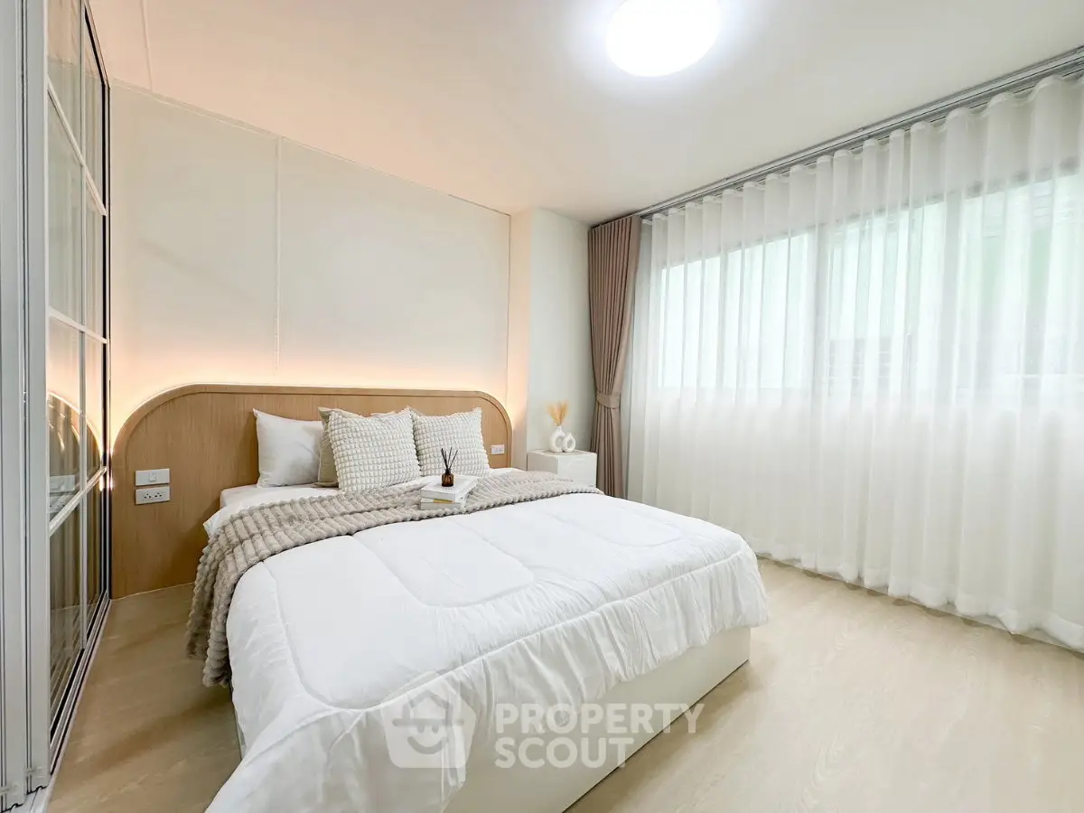 Bright and cozy bedroom with modern decor and large window for natural light.