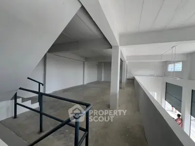 Spacious industrial-style interior with concrete floors and modern railing, ideal for versatile commercial use.