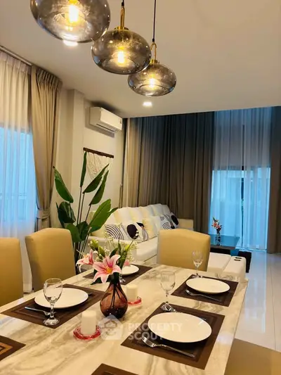 Elegant living room with modern decor and dining area, featuring stylish lighting and cozy ambiance.