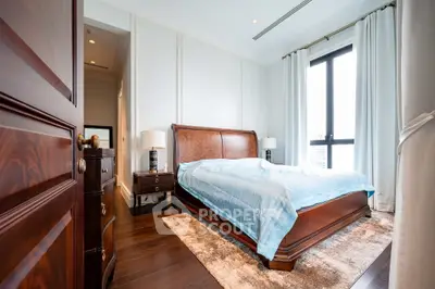 Luxurious bedroom with elegant wooden furniture and large window view.