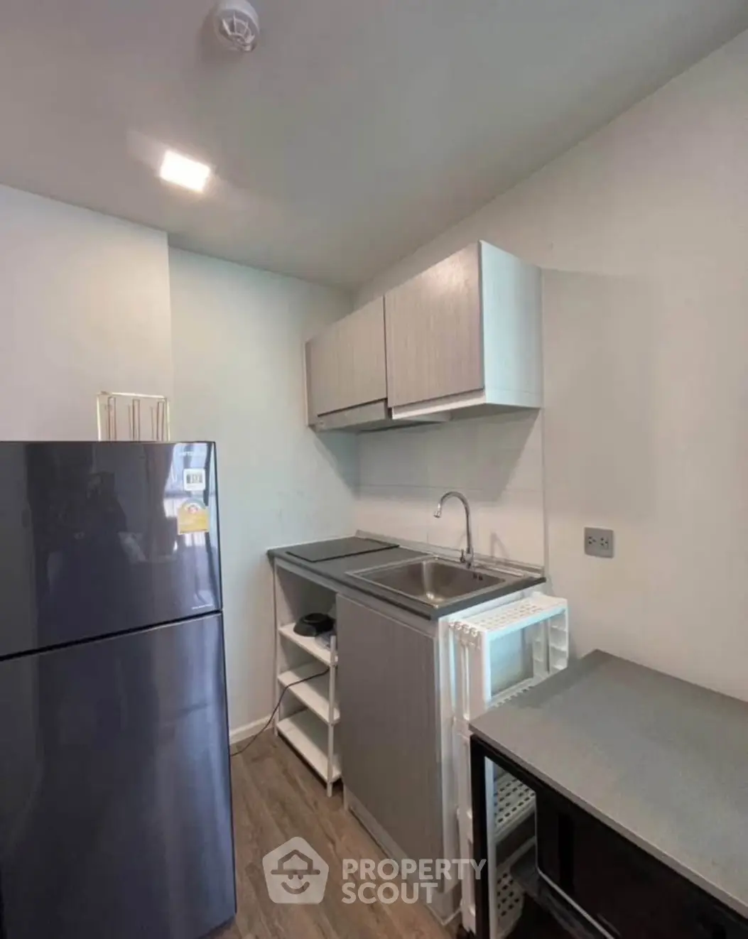 Compact modern kitchen with sleek cabinetry and stainless steel appliances in a cozy apartment.