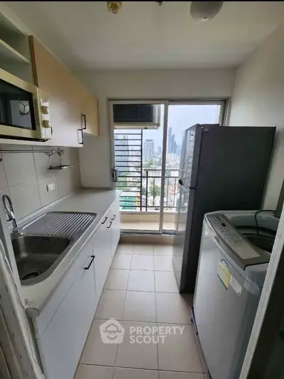 Modern kitchen with balcony view, featuring sleek appliances and ample counter space in a high-rise apartment.