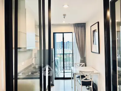 Modern apartment kitchen with dining area and city view balcony.