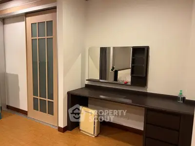 Modern bedroom with sleek wooden furniture and sliding door, featuring a stylish vanity mirror.