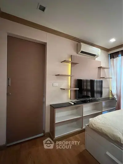 Modern bedroom with sleek TV unit and air conditioning, featuring stylish shelving and warm lighting.