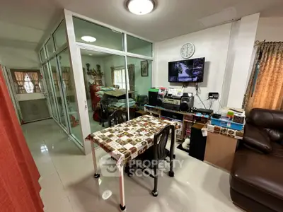 Cozy living room with glass partition, dining table, and entertainment setup.