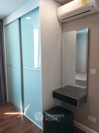 Modern bedroom with sleek sliding closet doors and stylish vanity area.