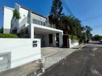 Modern two-story house with driveway and lush greenery in a suburban neighborhood.