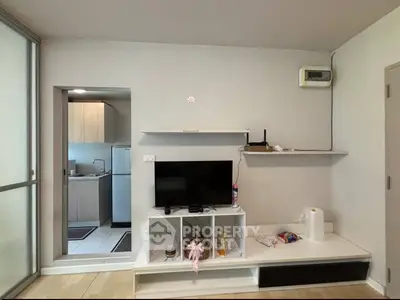 Modern living room with sleek TV unit and adjacent kitchen area in a stylish apartment.