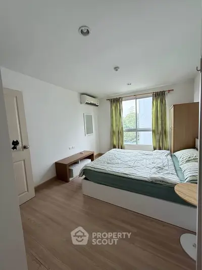 Bright and airy bedroom with large window and modern furnishings in a stylish apartment.