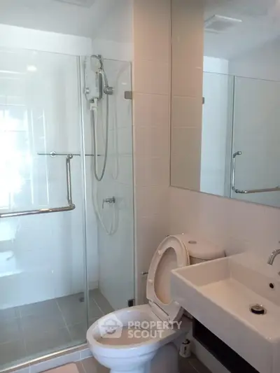Modern bathroom with glass shower and sleek fixtures in contemporary home.