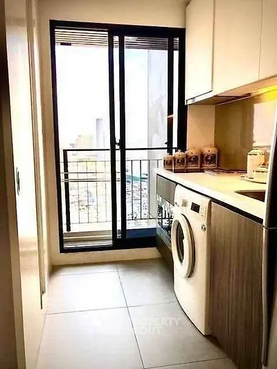 Modern kitchen with washing machine and balcony view in urban apartment.