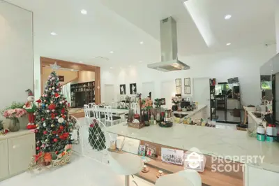 Spacious kitchen with modern island and festive Christmas decor, featuring open layout and elegant lighting.