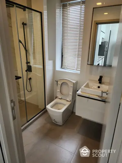 Modern bathroom with sleek glass shower enclosure, elegant vanity, and natural light filtering through blinds, perfect for a contemporary home.