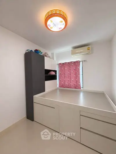 Modern bedroom with built-in storage and air conditioning, featuring a stylish ceiling light and pink curtains.