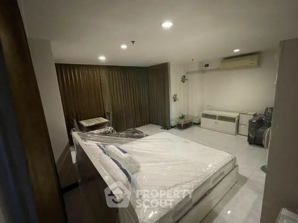 Spacious bedroom with modern furnishings and air conditioning in a well-lit apartment.
