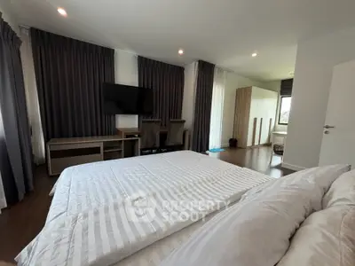 Spacious modern bedroom with elegant decor and large windows for natural light.