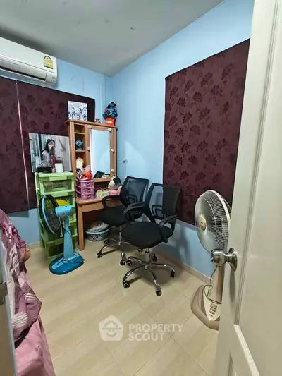 Cozy small bedroom with office chairs and fans, ideal for a compact home office setup.