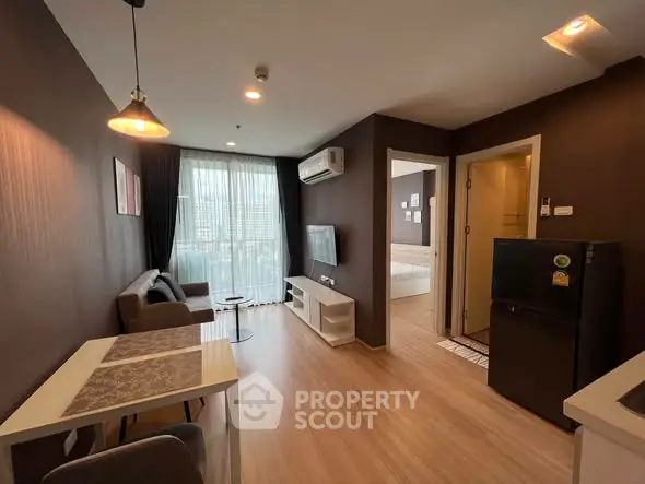 Modern living room with open layout and natural light, featuring a cozy seating area and sleek furnishings.