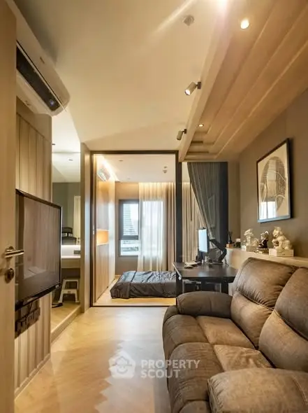 Modern living room with cozy sofa and stylish decor leading to a bedroom with natural light.