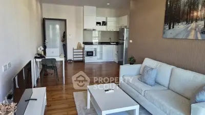 Modern living room with open kitchen, wooden flooring, and stylish decor in a cozy apartment.