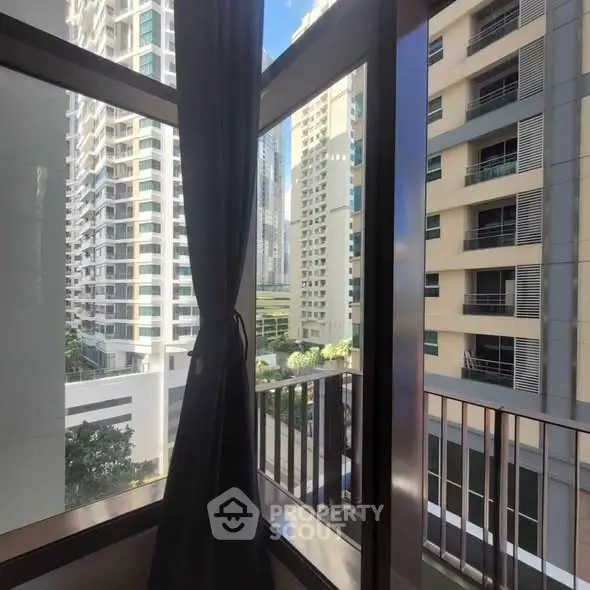 Stunning urban view from a high-rise apartment window with modern buildings in the background.