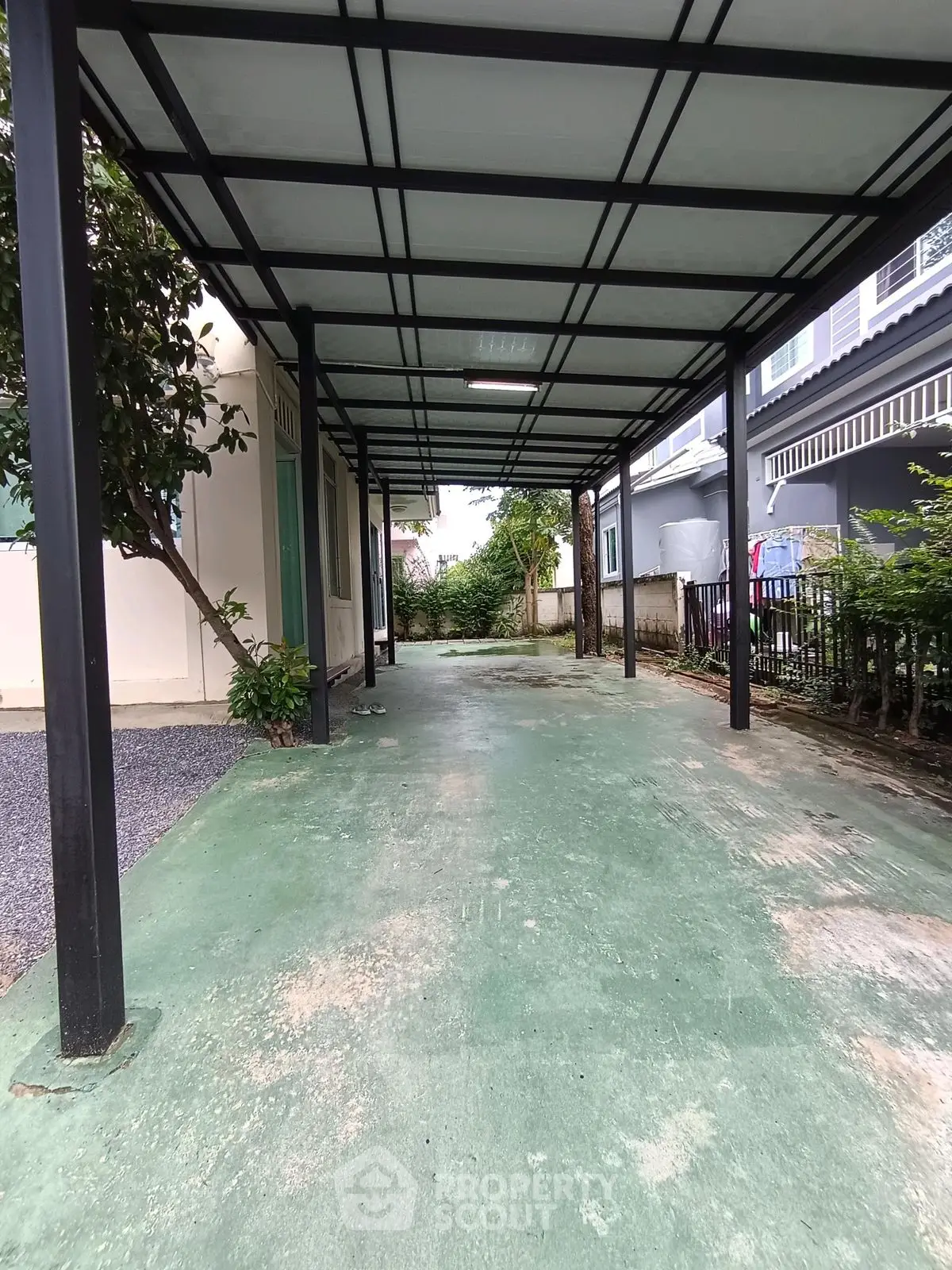 Spacious covered parking area with green flooring and metal roof structure.