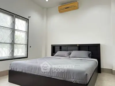 Modern bedroom with sleek black bed frame and air conditioning
