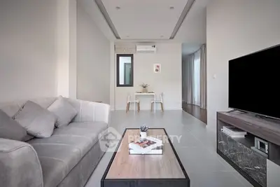 Modern living room with sleek furniture and neutral tones, featuring a cozy sofa and stylish coffee table.