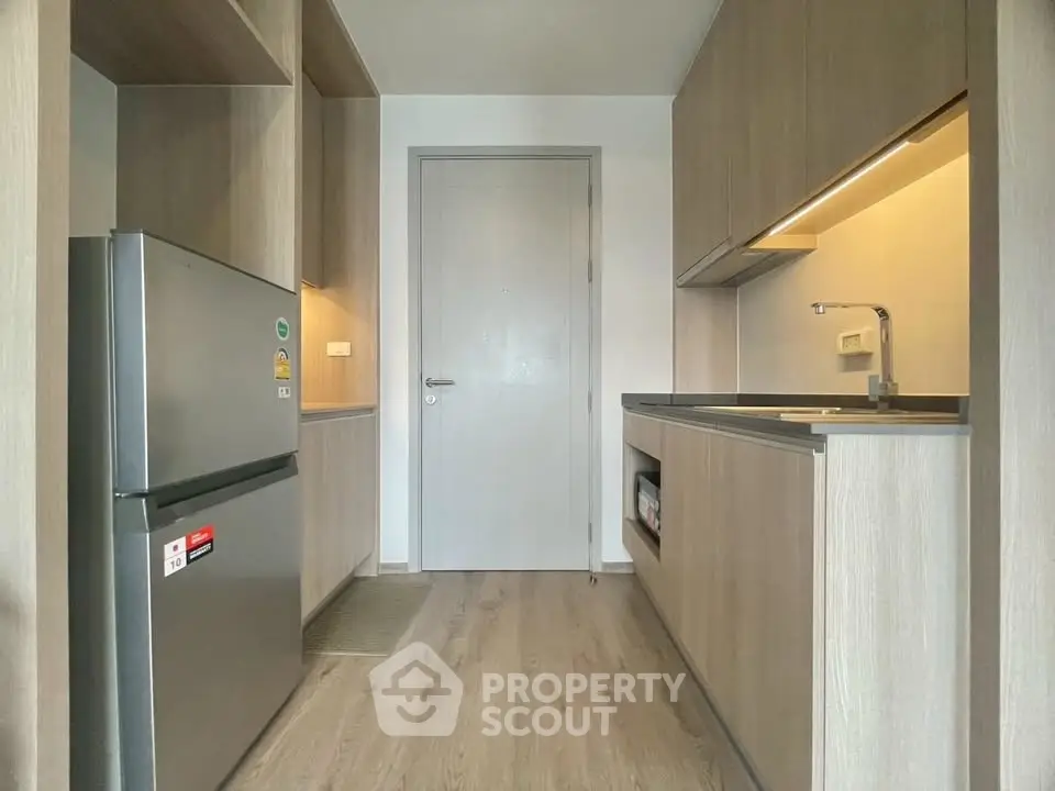 Modern kitchen with sleek cabinetry and stainless steel fridge in compact layout.