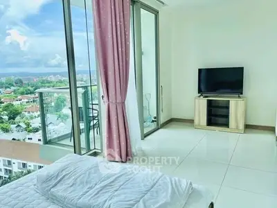 Bright bedroom with balcony and scenic view, featuring modern decor and a flat-screen TV.