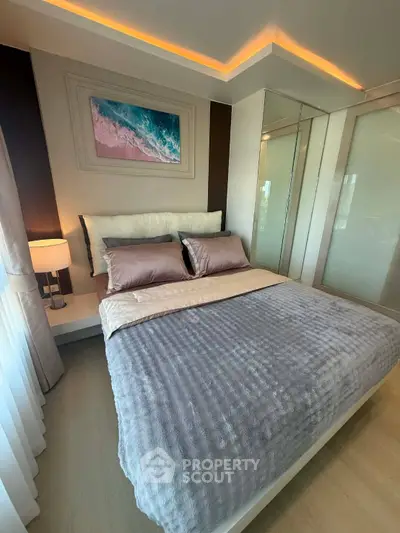 Luxurious bedroom with modern decor and ambient lighting, featuring a plush bed and elegant artwork.