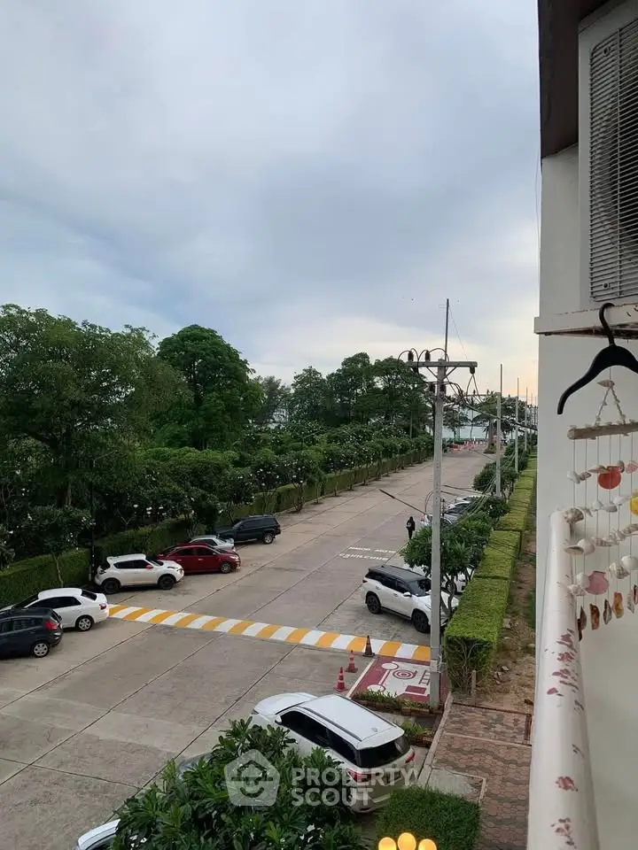 Scenic view from balcony overlooking lush greenery and parked cars, perfect for nature lovers.