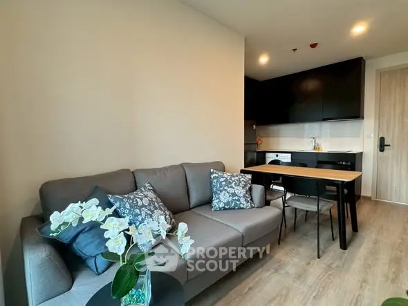 Modern living room with cozy sofa and stylish kitchen in open layout apartment.
