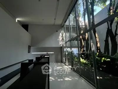 Modern office space with large windows and garden view, featuring sleek design and abundant natural light.