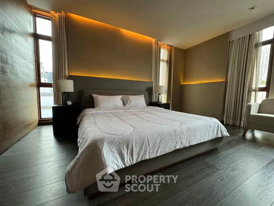 Luxurious bedroom with modern lighting and large windows in upscale apartment.